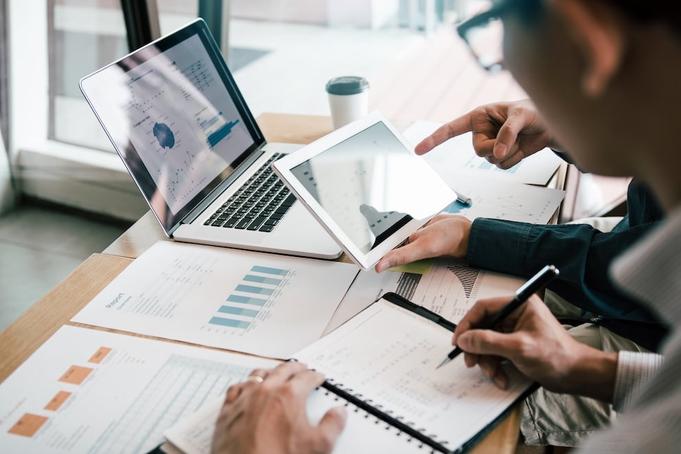 Business partnership coworkers using a tablet to analysis graph company financial budget report and cost work progress and planning for future in office room.